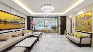 A spacious lobby with a chandelier, a large painting of a bridge, a sofa with cushions, and a bench. - 22Land Residence Hotel 2 (Hanoi)