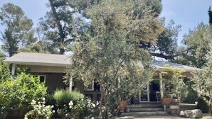 A house with a covered porch, a front yard with a tree and white roses, and a gravel driveway. - Pets Welcome <br>Private Home on 2 Acres<br>Hiking, biking, Trails <br> (Altadena)