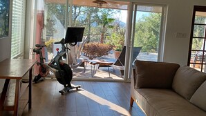 A spacious living area with a wooden floor, a sofa, a ceiling fan, and a view through large glass doors to an outdoor patio with a table and chairs. - Pets Welcome <br>Private Home on 2 Acres<br>Hiking, biking, Trails <br> (Altadena)
