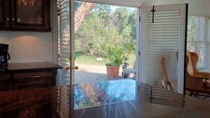 An open doorway leading to a patio with a potted plant, a guitar, and a chair. - Pets Welcome <br>Private Home on 2 Acres<br>Hiking, biking, Trails <br> (Altadena)