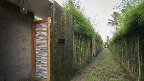 A narrow pathway flanked by bamboo and a wall with a colorful, vertical pattern. - Prema Uja Villas (Ubud)