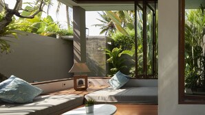 A modern living room with a sofa, a small table, and a potted plant. - Prema Uja Villas (Ubud)