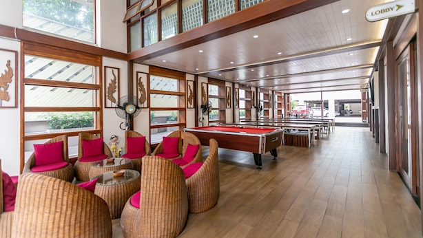 Un espace intérieur vaste et lumineux, doté d’une table de billard, de meubles en osier et de grandes fenêtres.
