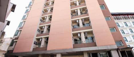 Un edificio residencial de varios pisos con balcones, estacionamiento techado y entrada con portón.