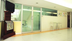 A spacious lobby with a staircase, a glass door entrance, and a small table with chairs. - Meesook Residence (Nonthaburi)