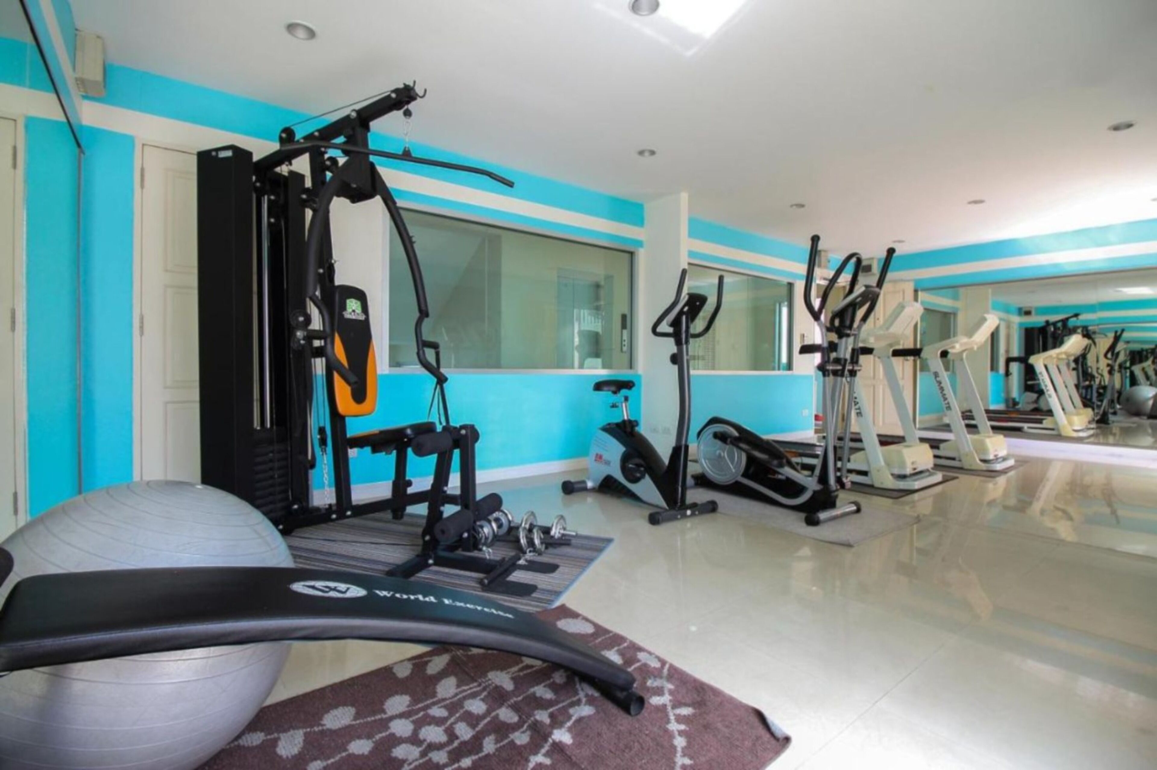 A home gym with exercise equipment, a large mirror, and a blue and white color scheme.