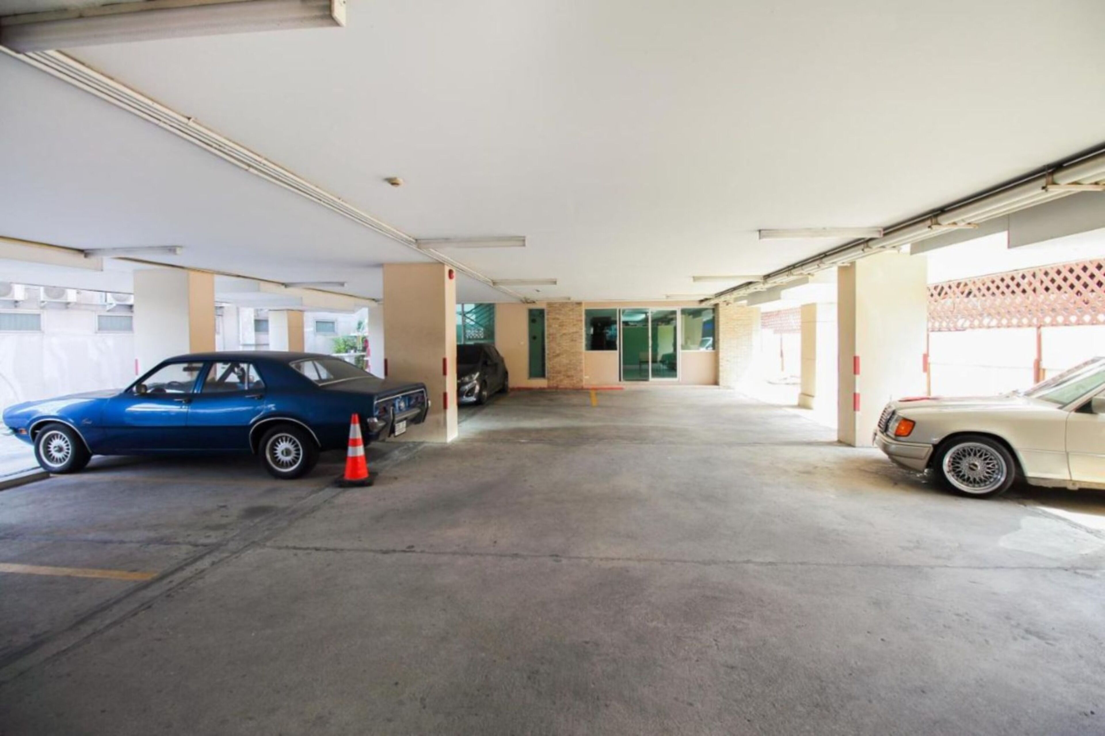 A covered parking area with two cars parked, one blue and one white.