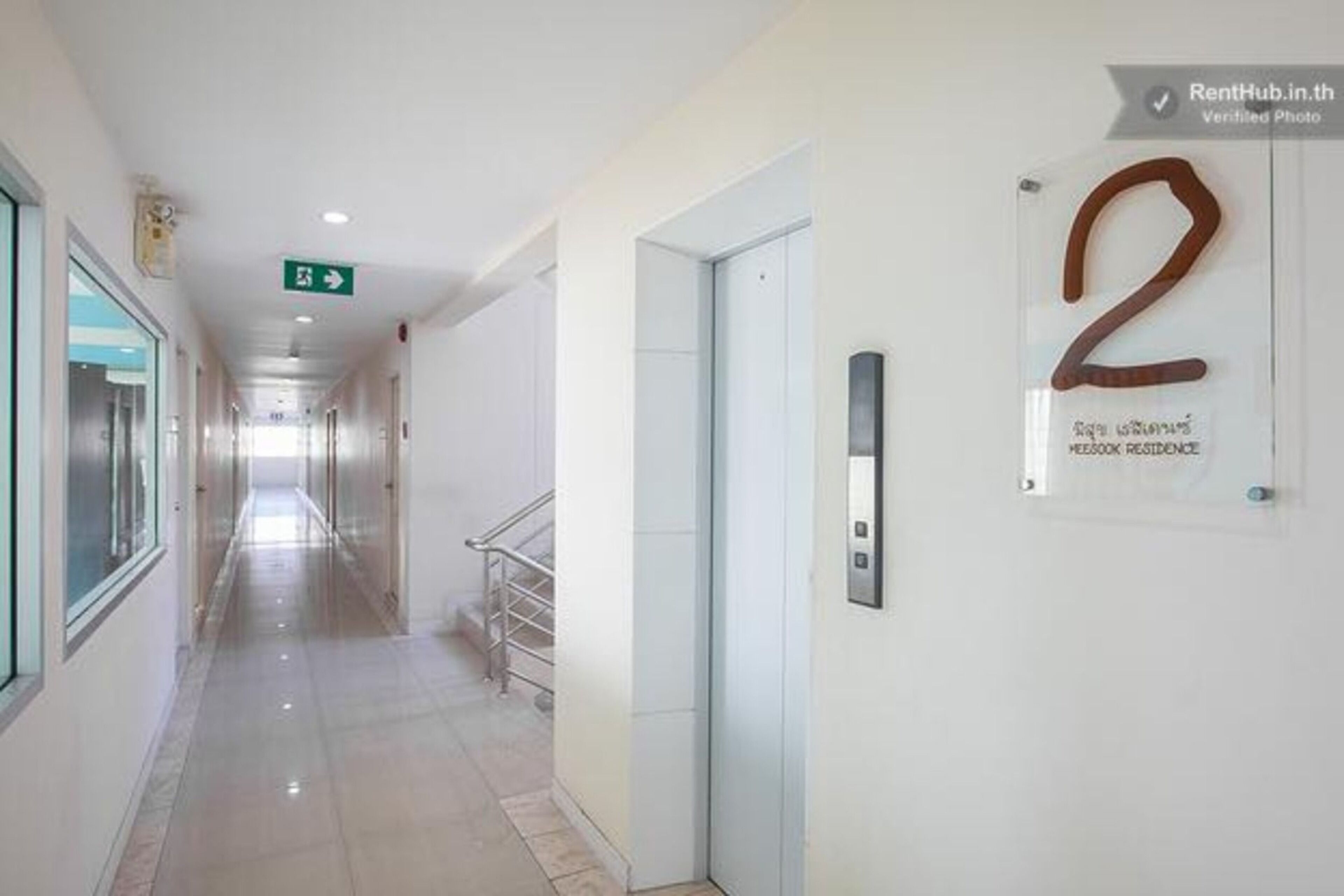 A hallway with a clear floor, a door labeled '2', and a sign indicating an exit.