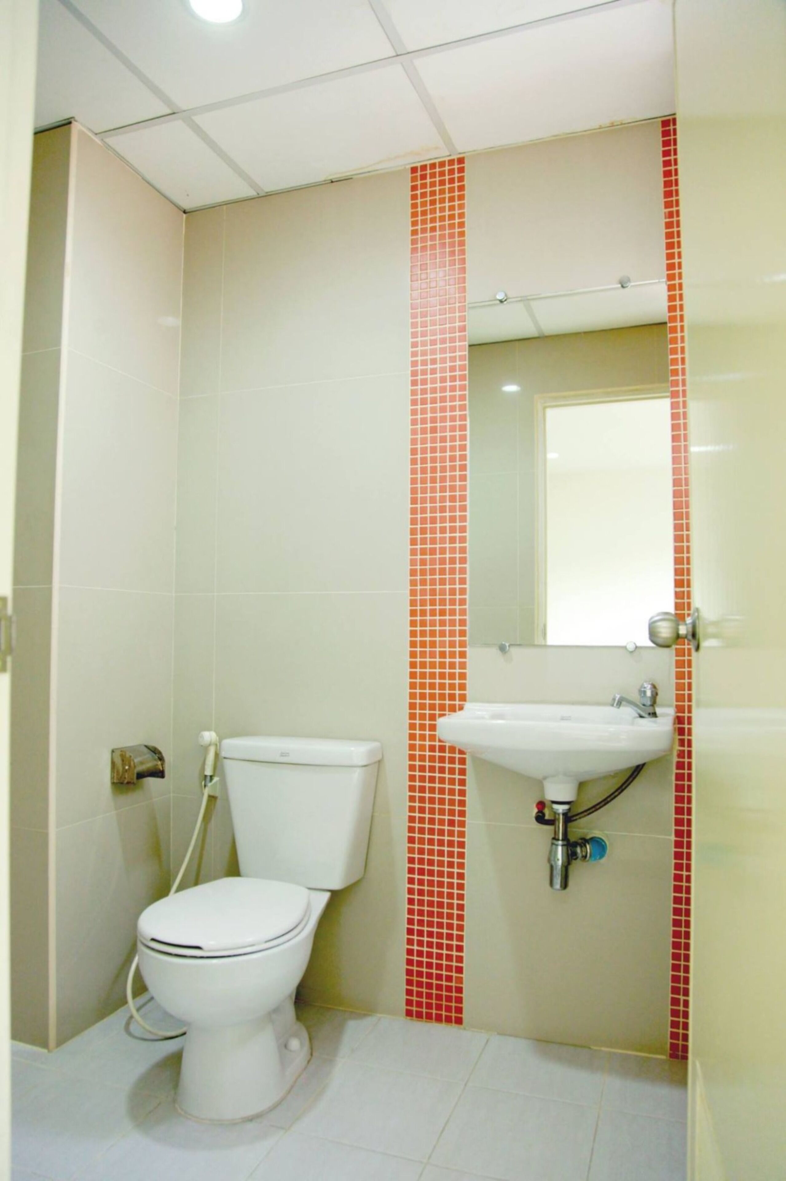 A small bathroom with a toilet, sink, and mirror.