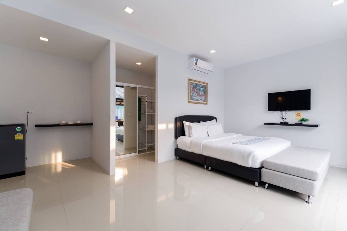 A modern hotel room with a bed, a TV, a desk, and a wardrobe.