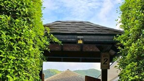 A covered outdoor area with a pool, surrounded by lush greenery. - Lespalm Taraburi Pool Villa (Si Sunthon)