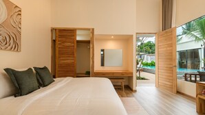 A modern bedroom with a large bed, a wooden desk, a mirror, and a view of a swimming pool. - Lespalm Taraburi Pool Villa (Si Sunthon)
