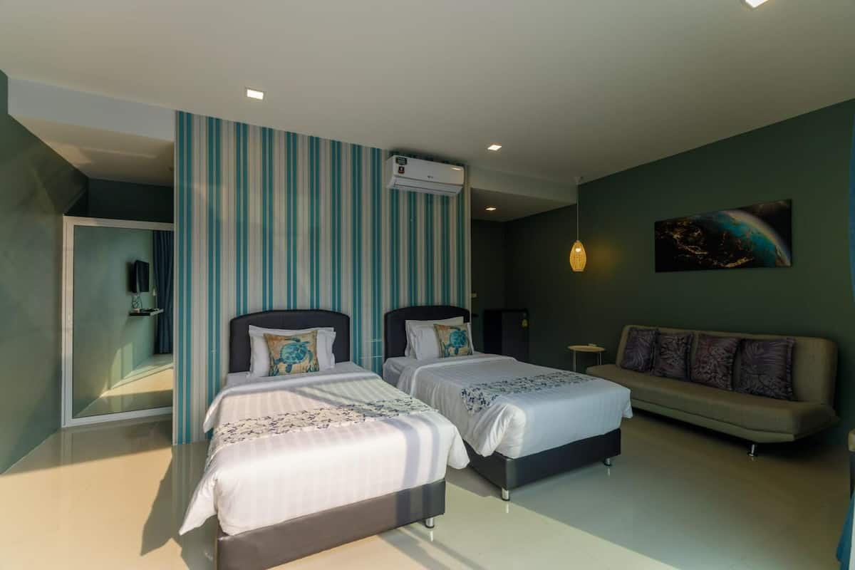 A hotel room with two beds, a sofa, a mirror, and a painting on the wall.