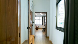 Un pasillo con suelo de madera, un armario y una ventana con cortinas.