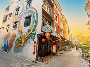 A building with a colorful dragon mural, a traditional Chinese restaurant entrance, and a clear sky. - Taladnoi Paint House (Bangkok)