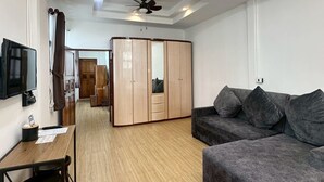 Una sala de estar moderna con piso de madera, un sofá gris, un televisor y un armario.