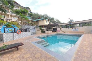 Une piscine avec une terrasse carrelée, un banc et une bouée de sauvetage.