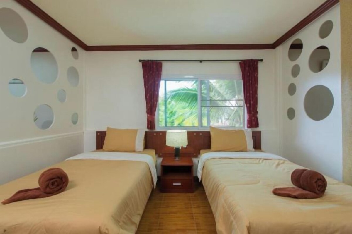 Een hotelkamer met twee bedden, een raam met gordijnen en ronde decoraties aan de muur.