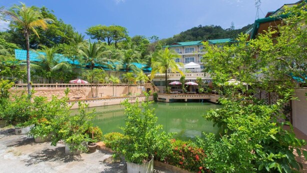 A serene courtyard with a central water feature, surrounded by lush greenery and traditional architecture. - Patong Rai Rom Yen Resort SHA (Patong)