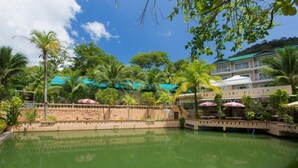 A resort with a pool surrounded by palm trees and a building with balconies. - Patong Rai Rom Yen Resort SHA (Patong)