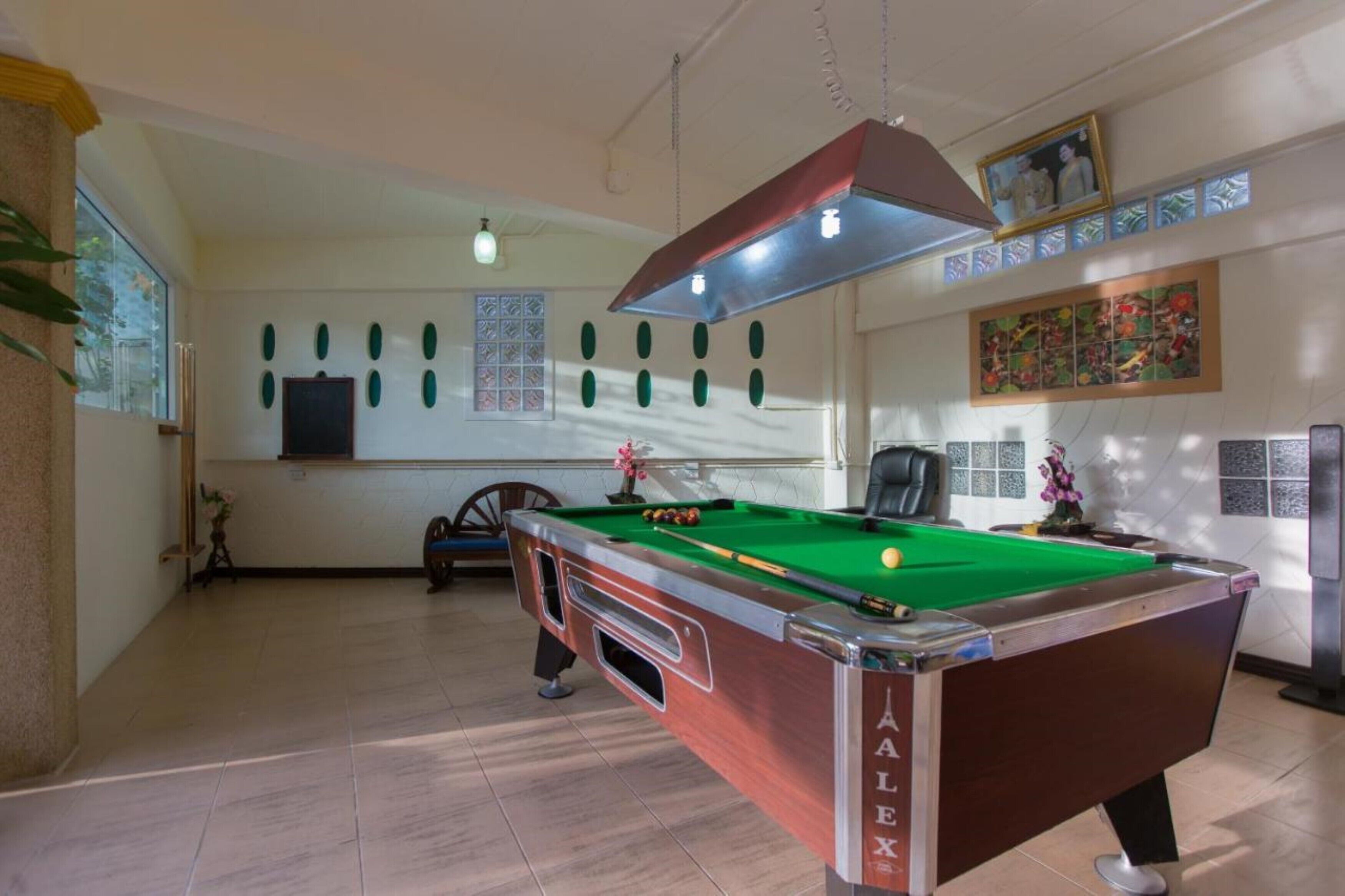 A pool table in a room with a high ceiling, decorative wall panels, and a framed picture above the table.