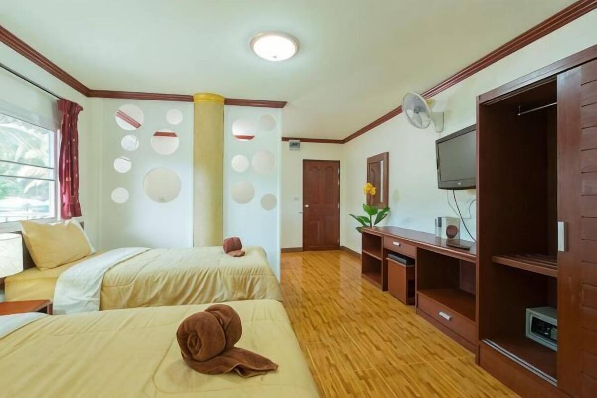 A hotel room with two beds, a TV, a desk, and a wardrobe.