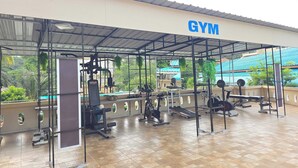 A gym with exercise equipment, a roofed structure, and a view of greenery. - Patong Rai Rom Yen Resort SHA (Patong)
