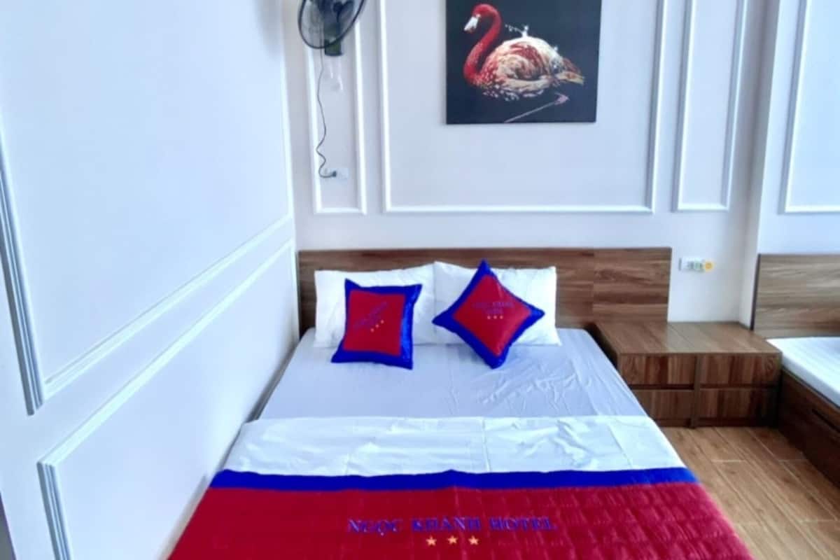 Quarto de hotel com uma cama, ar-condicionado fixado na parede, ventilador fixado na parede e uma pintura de um flamingo.