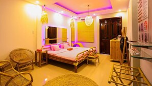 A bedroom with a bed, two wicker chairs, a bedside table, a dresser, and a mirror. - Long Den Do Hotel (Ho Chi Minh City)