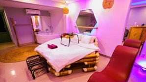 A room with a bed, a red chair, a small table, a mirror, and a wooden structure. - Long Den Do Hotel (Ho Chi Minh City)