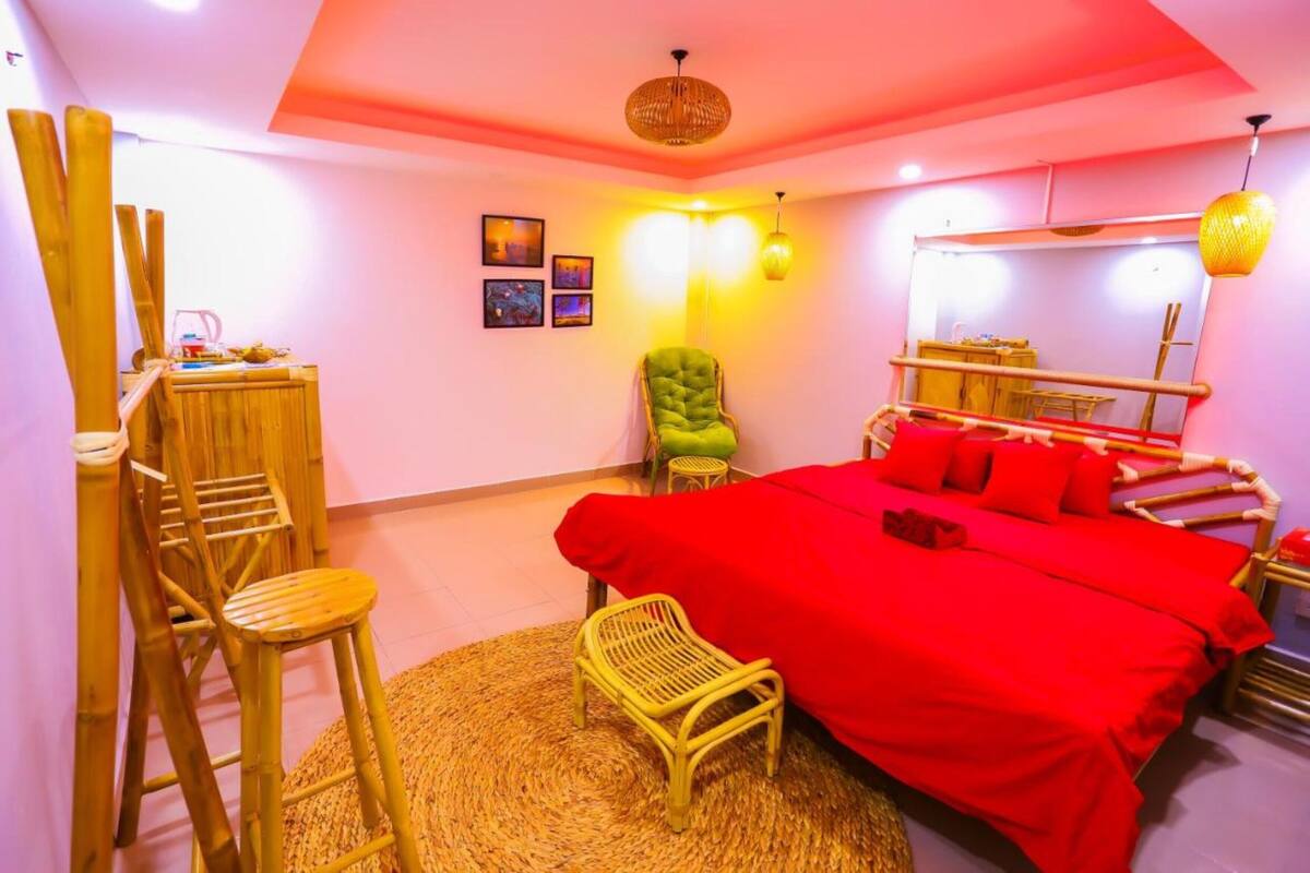 Quarto com cama, cadeira, mesa pequena e espelho.
