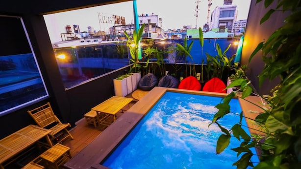 A rooftop pool area with wooden furniture and potted plants. - Long Den Do Hotel (Ho Chi Minh City)