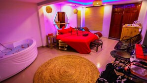 A modern bedroom with a red bed, a white bathtub, and a woven rug. - Long Den Do Hotel (Ho Chi Minh City)
