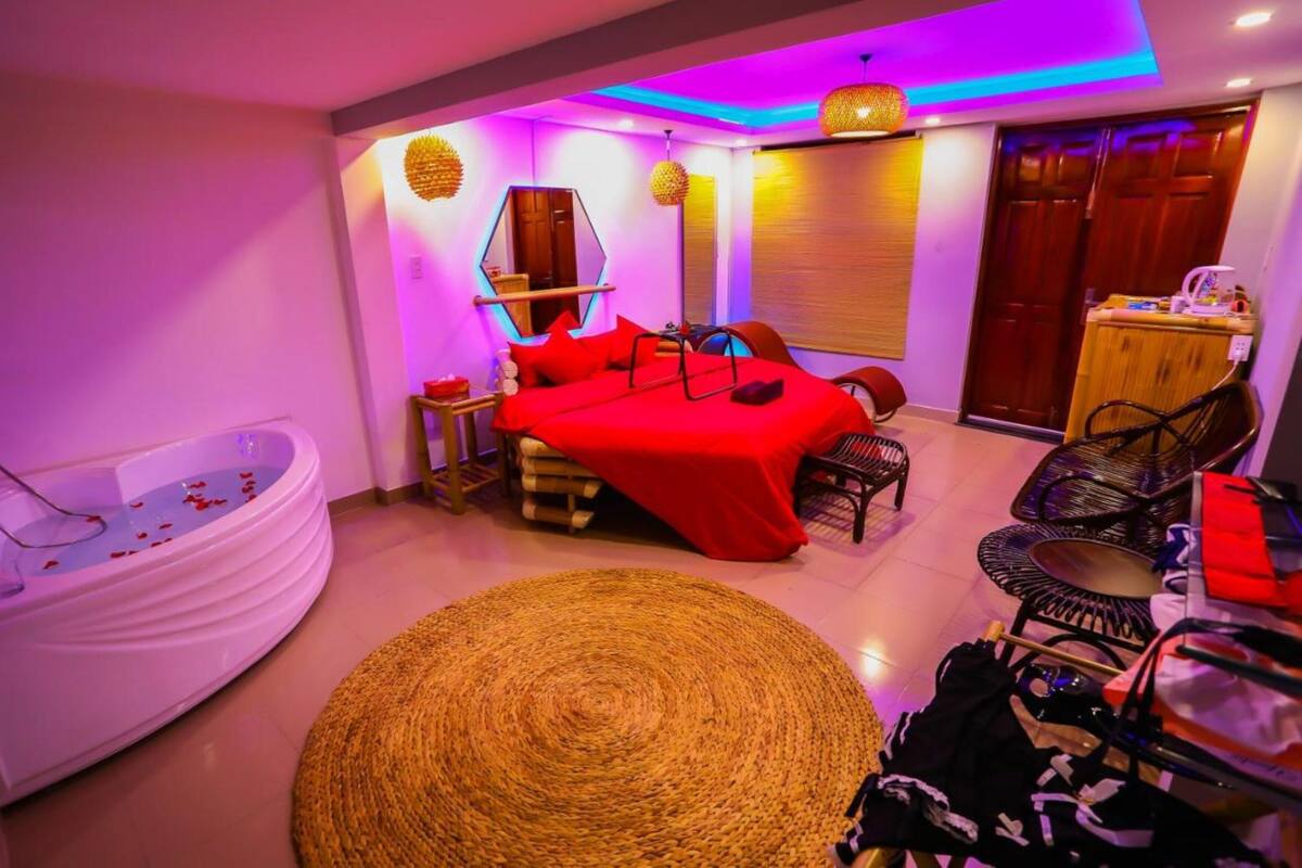 Quarto moderno com cama vermelha, banheira branca e tapete tecido.