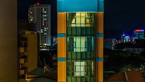 A multi-story hotel with a prominent glass facade, a visible staircase, and signage for 'Hotel KHANH VY' and 'Motel SAU DUNG'. - Khanh Vy Hotel (Ho Chi Minh City)