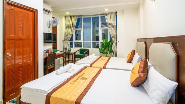 A hotel room with two beds, a desk, a chair, a TV, and a window with curtains. - Khanh Vy Hotel (Ho Chi Minh City)