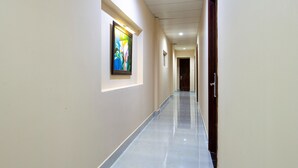 A long, narrow hallway with a marble floor and light-colored walls. There are framed artworks on the walls and a door at the end. - Khanh Vy Hotel (Ho Chi Minh City)