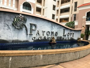 Une grande enseigne pour la résidence Patong Loof, avec piscine et éléments décoratifs.