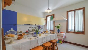 A kitchen with a dining area, featuring a table set for a meal, a hanging light fixture, and a window with curtains. - Antica "casa Cervade" Pica Venetian Farmhouse, Preserved Original From 1902 (Fontanelle)