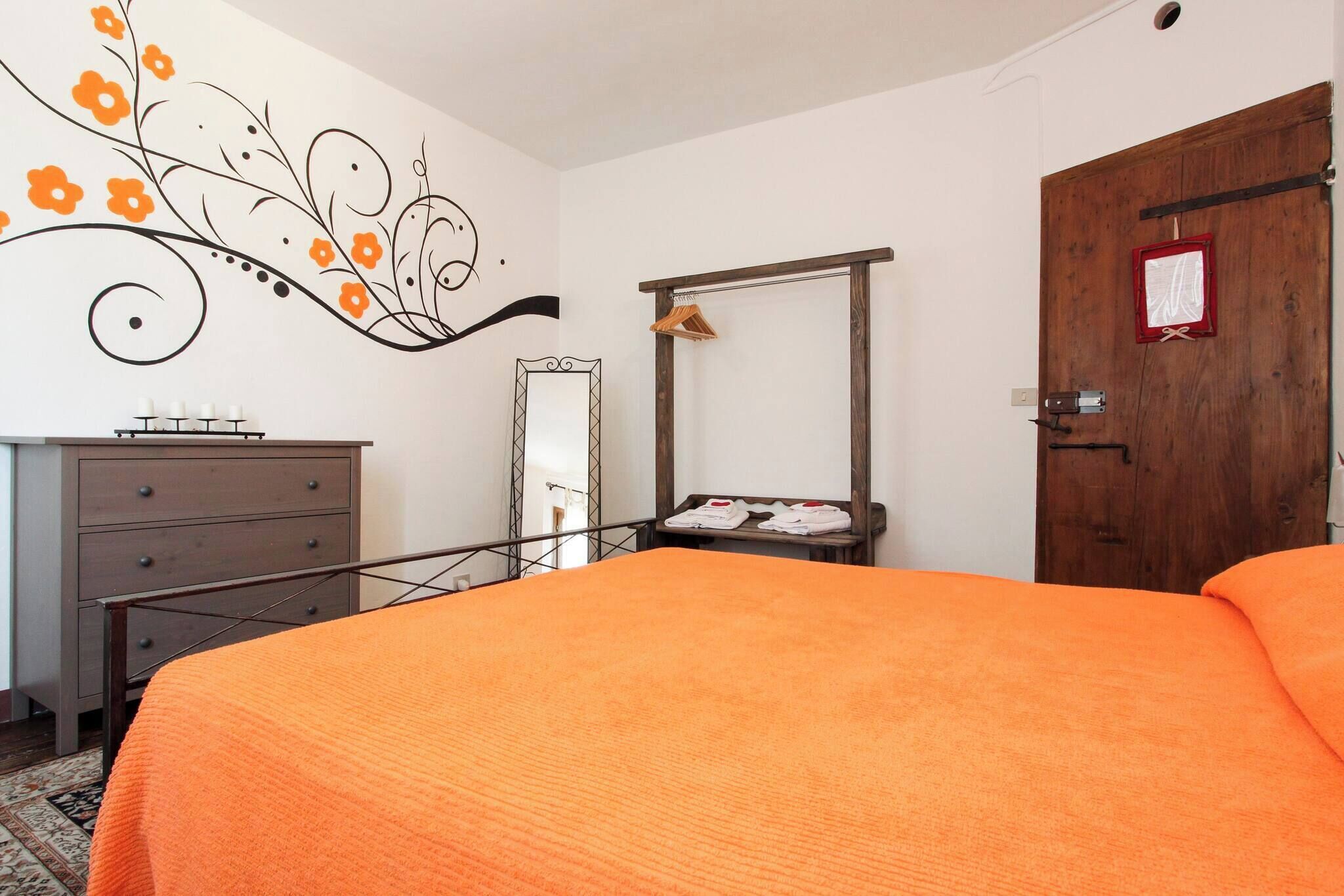 A bedroom with a bed, a dresser, a mirror, and a door with a red sign.