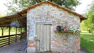 Traditional single-story structure with a sloped roof and wooden door, set amidst a green open area.