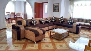 Una sala de estar con un sofá modular, una mesa de centro y un comedor con sillas y una mesa.