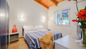 A bedroom with a bed, bedside table, and a window with a view of greenery. - Residence Emmesse Trilocal 3 Rooms (Zambrone)