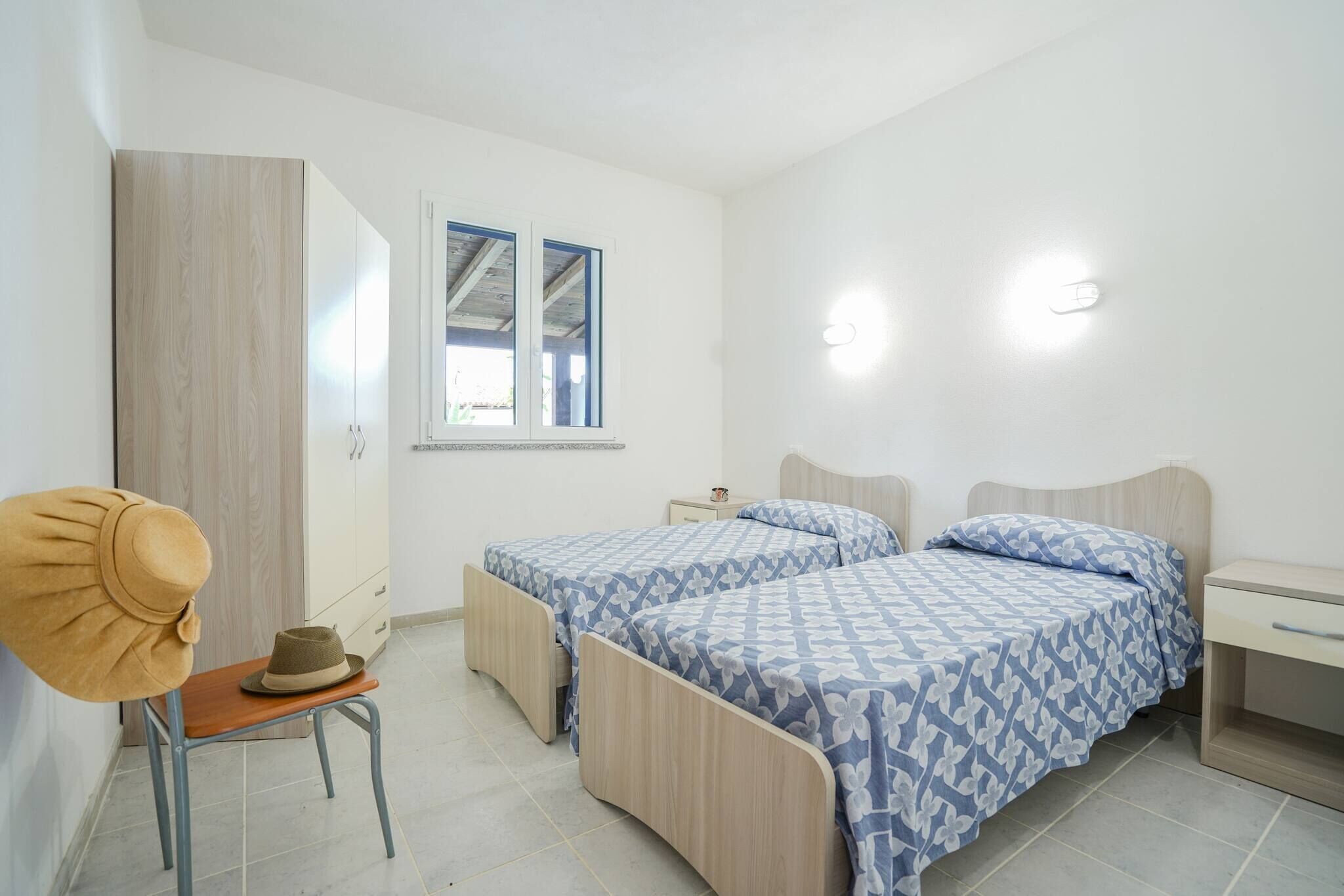 A bedroom with two beds, a wardrobe, a chair, and a nightstand.