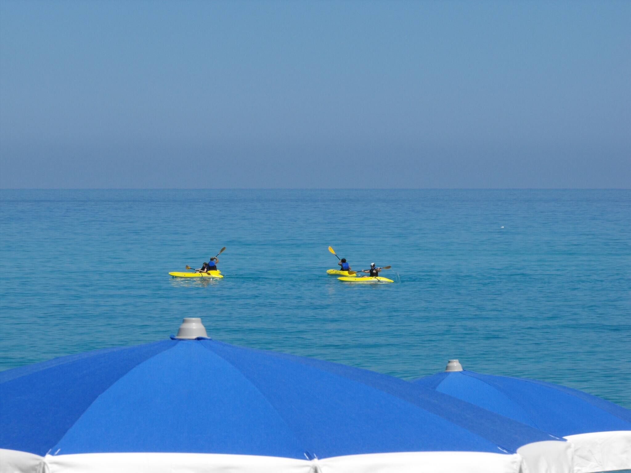 Two kayaks on calm water with a clear sky.