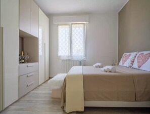 A bedroom with a bed, a nightstand, a dresser, and a window with curtains.