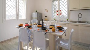 A dining area with a table set for four, a kitchen with a sink and cabinets, and a window with a life preserver decoration.