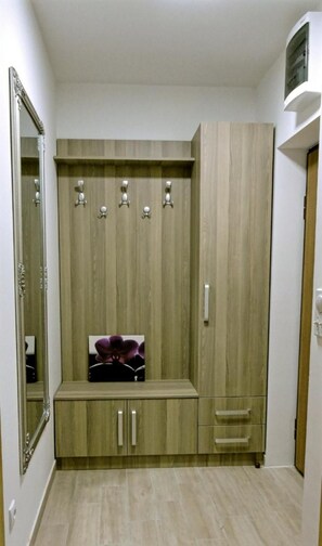 Un armario de madera con un espejo, una repisa con un objeto morado y una puerta con manija.