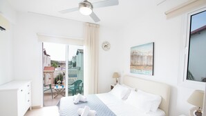 Hotellihuone, jossa on sänky, työpöytä, tuoli ja parveke, jolta on näkymä.