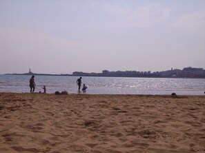 A beach with sand and water, a distant city skyline, and a lighthouse. - Holidays in Vieste in Charming Villas - 2 (Vieste)